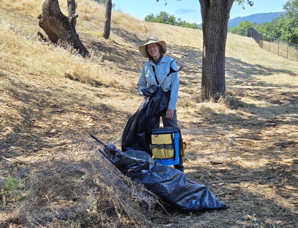 Jonalee with old cages and bags of shreded drip line.